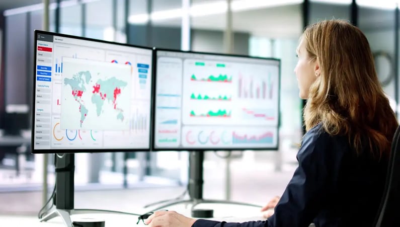 woman at double screens looking at analytics dashboards